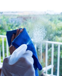 close up of hands or man or woman cleaning  glass of the window of the home with spray to kill every germ or bacteria inside the house - housewife working in the workhouse washing and cleaning with disinfectant