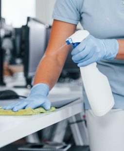 Close up view of woman in protective gloves that cleaning tables in the office.